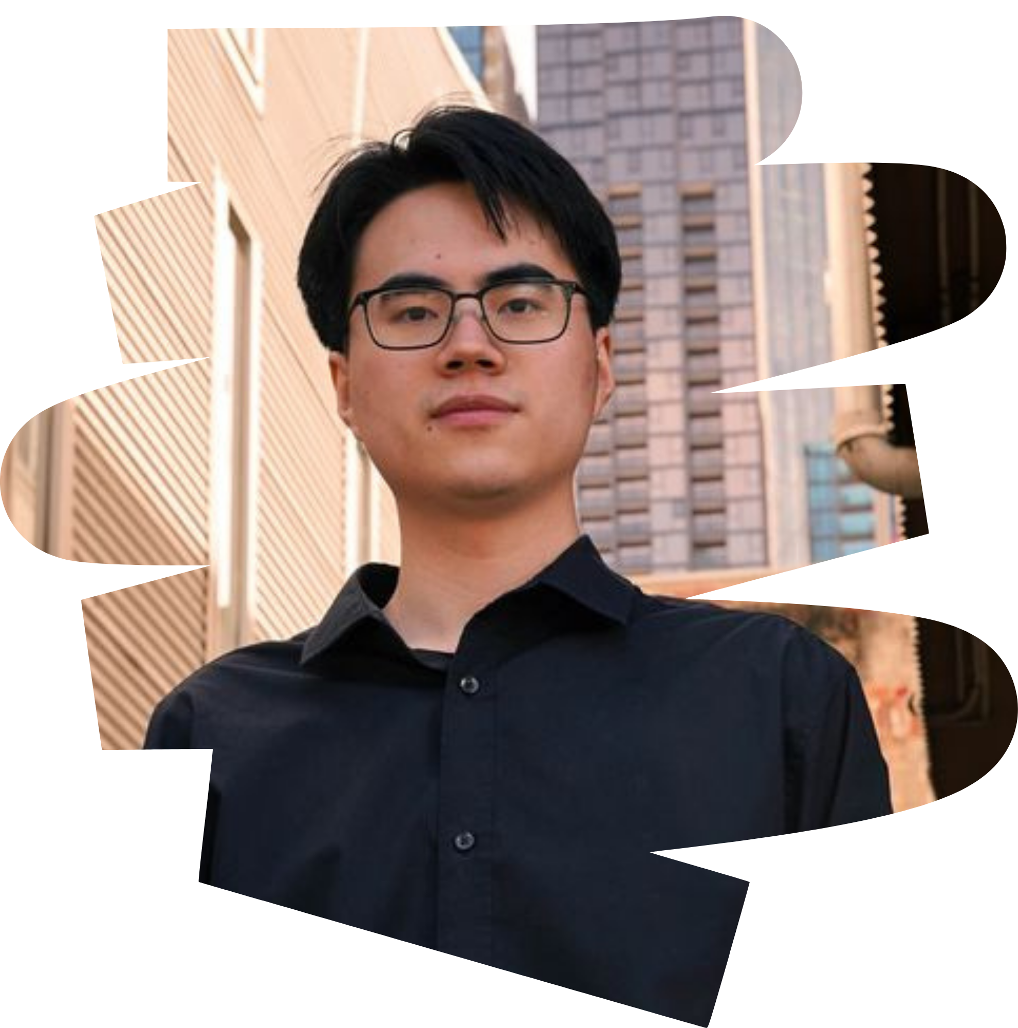 Young asian man standing in front of buildings looking down towards the camera